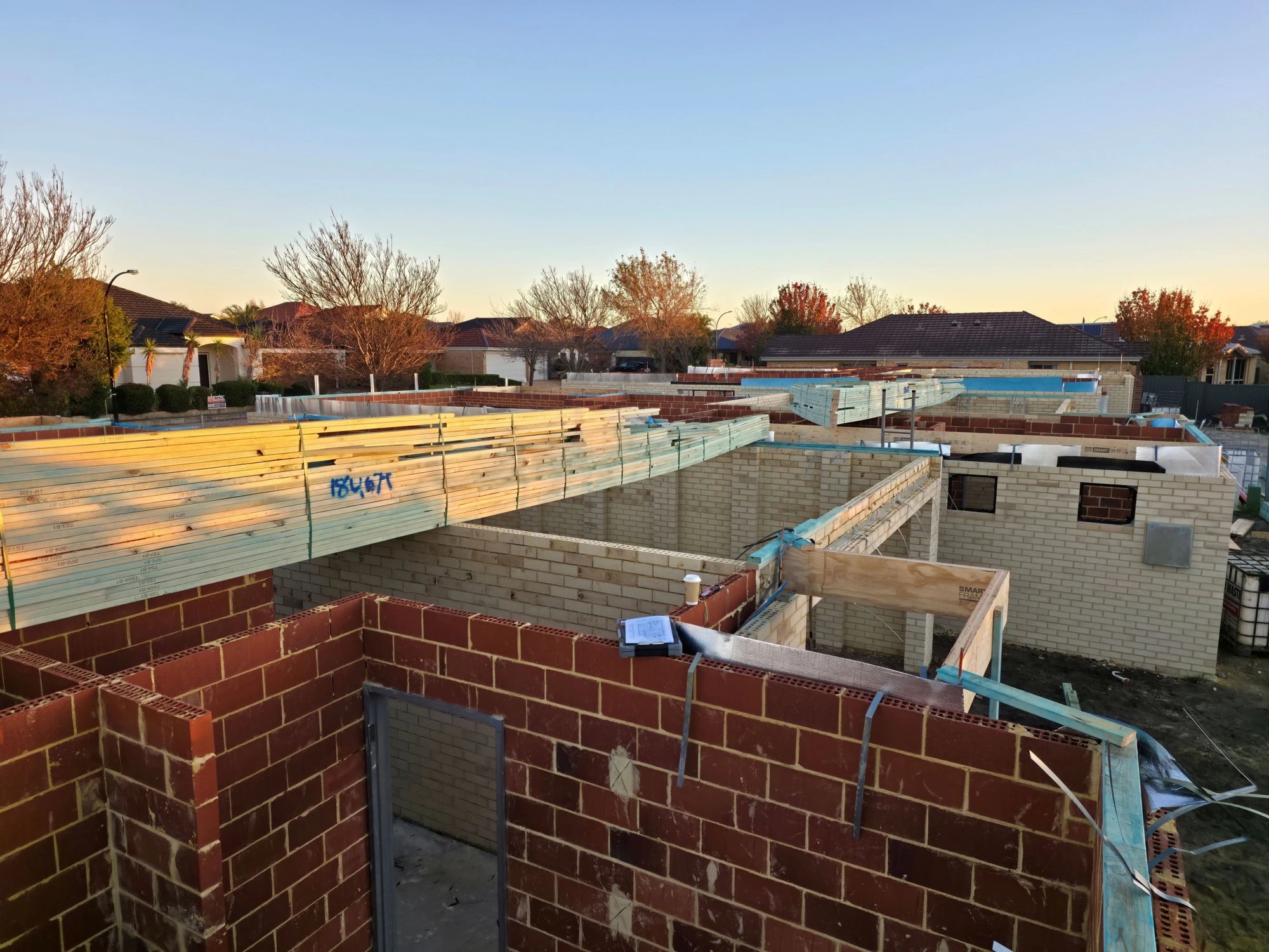 Timber packs on brickwork at sunrise, ready for the roof